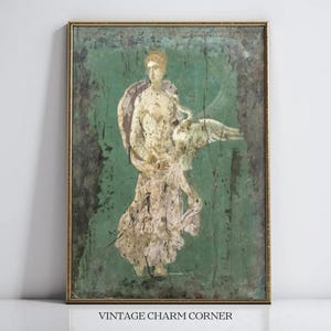May include: Vintage framed artwork featuring a classical figure with a swan against a distressed green background. The figure is depicted in muted tones of beige and white, with a gold frame. The text "VINTAGE CHARM CORNER" is at the bottom.