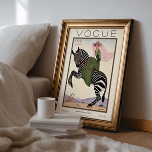Digitally restored 1926 Vogue magazine cover titled Southern Fashions Number, featuring a stylish woman in a flowing green dress and pink hat riding a zebra in a desert landscape with giraffes and mountains. Vintage Art Deco fashion illustration digital download ideal for gallery walls, eclectic decor, and gifts for fashion history and vintage art lovers.