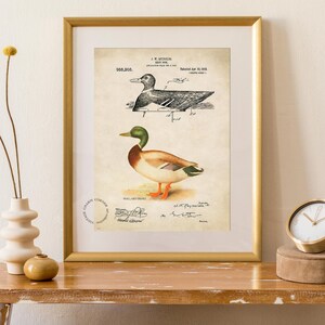 Vintage duck decoy wall art featuring a 1910 patent sketch and watercolor illustration of a mallard drake. Perfect for farmhouse, rustic, lodge, or hunting-themed decor. This antique bird print is a high-resolution digital download for instant use. Ideal for vintage art lovers, birdwatchers, or as a Father's Day gift. Styled for cottagecore, nature-inspired, or Americana interiors. Unique historical artwork to enhance your space with charm and character.