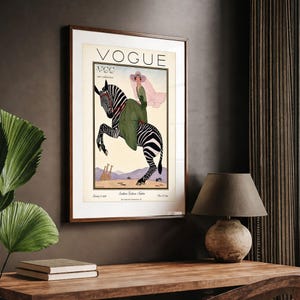 Digitally restored 1926 Vogue magazine cover titled Southern Fashions Number, featuring a stylish woman in a flowing green dress and pink hat riding a zebra in a desert landscape with giraffes and mountains. Vintage Art Deco fashion illustration digital download ideal for gallery walls, eclectic decor, and gifts for fashion history and vintage art lovers.