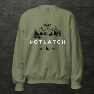 May include: A green sweatshirt with a black graphic design of mountains, trees, and the text "IDAHO POTLATCH EST. 1906".