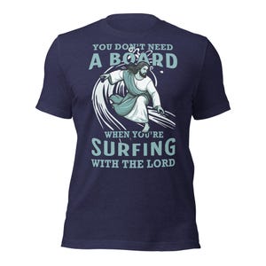 May include: A navy blue t-shirt with a graphic of Jesus surfing on a wave. The text reads "You don't need a board when you're surfing with the Lord."