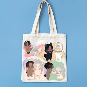 Op de afbeelding: Een crèmekleurige draagtas met cartoonillustraties van verschillende personages in verschillende outfits en poses. De personages zijn geplaatst tegen kleurrijke, abstracte achtergronden. De tas hangt aan een lichtblauwe muur.