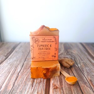 May include: A bar of orange and yellow soap with the text "Sweet Swirl Natural & handcrafted Turmeric & Tea Tree Aloe Vera Soap Net Weight 4.5oz" on the label.