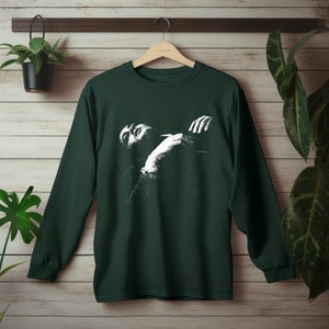 May include: A dark green long-sleeved t-shirt with a white graphic print of a person embracing themself.