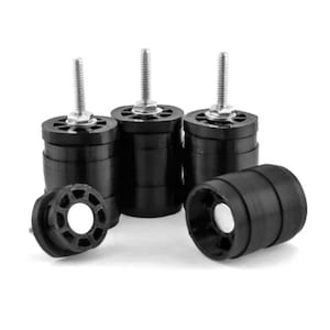 May include: Four black adjustable height furniture feet with threaded metal posts. Each foot has a round base and a textured surface.