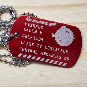 May include: Red metal dog tag with a white ghostbusters logo and text that reads "Who you gonna call?"  Fairres Caleb D GBL-1138 Class IV Certified Central Arkansas GB