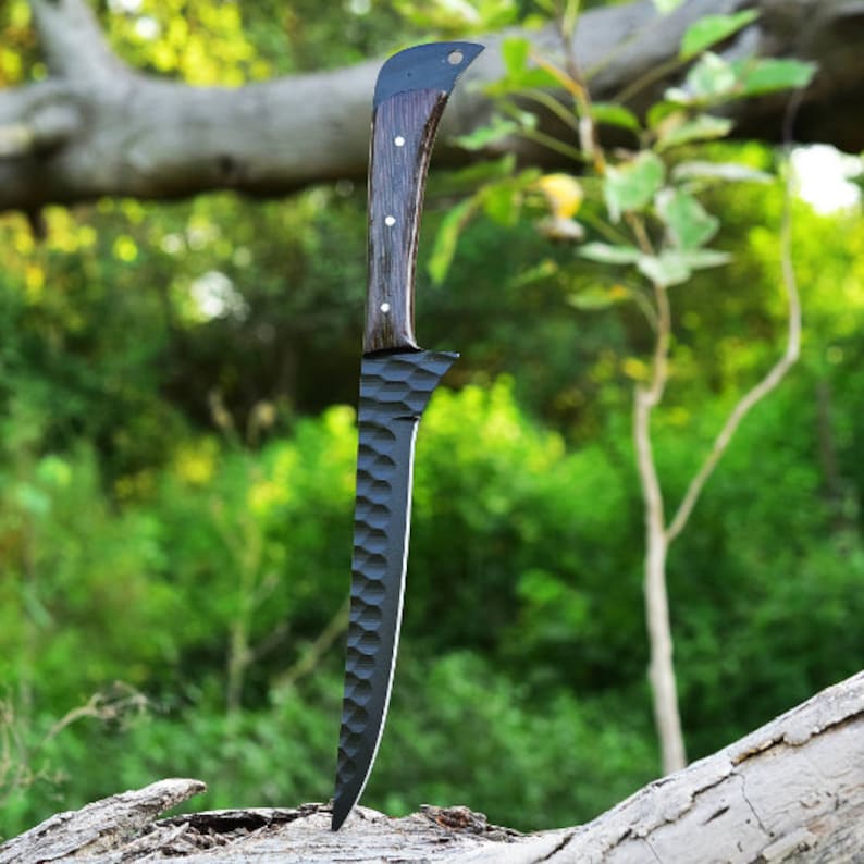 K&ouml;nnte beinhalten: Ein schwarzes und braunes Jagdmesser mit einer strukturierten Klinge und einem Holzgriff. Das Messer steht aufrecht auf einer Holzoberfl&auml;che.