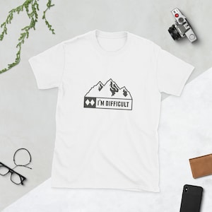 May include: White t-shirt featuring a black mountain range graphic and the text "I'M DIFFICULT". The tee shirt is made of a soft material and has a crew neck.