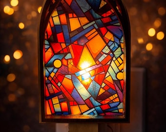 May include: A stained glass night light with a wooden frame. The colorful design features geometric shapes in red, orange, yellow, blue, and purple. The night light is plugged into a wall outlet and emits a warm glow.