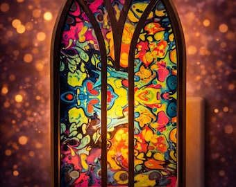 May include: A colorful stained-glass style night light with a wooden frame. The glass features a vibrant abstract design in shades of pink, blue, yellow, and orange. The night light plugs directly into a wall outlet.