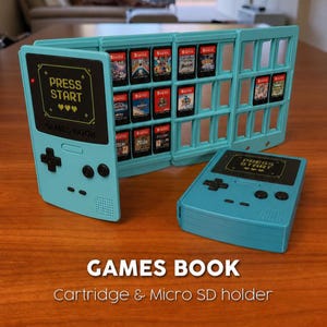 Op de afbeelding: Een lichtblauwe Games Book cartridge- en micro SD-kaarthouder, ontworpen als een retro handheld gameconsole. De houder is open en toont verschillende game cartridges. De tekst "PRESS START" is zichtbaar aan de voorkant.