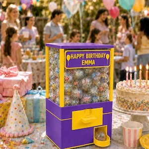 May include: A purple and yellow vending machine filled with clear plastic capsules. The front panel features a yellow sign with the text HAPPY BIRTHDAY EMMA and balloon icons. The machine has a dispensing slot at the bottom with a single capsule.