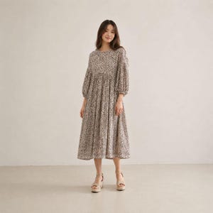 May include: A midi-length dress featuring a brown and white animal print pattern, a round neckline, and long puff sleeves with gathered cuffs. The dress has a fitted bodice that transitions into a loose, flowing skirt that falls below the knees.