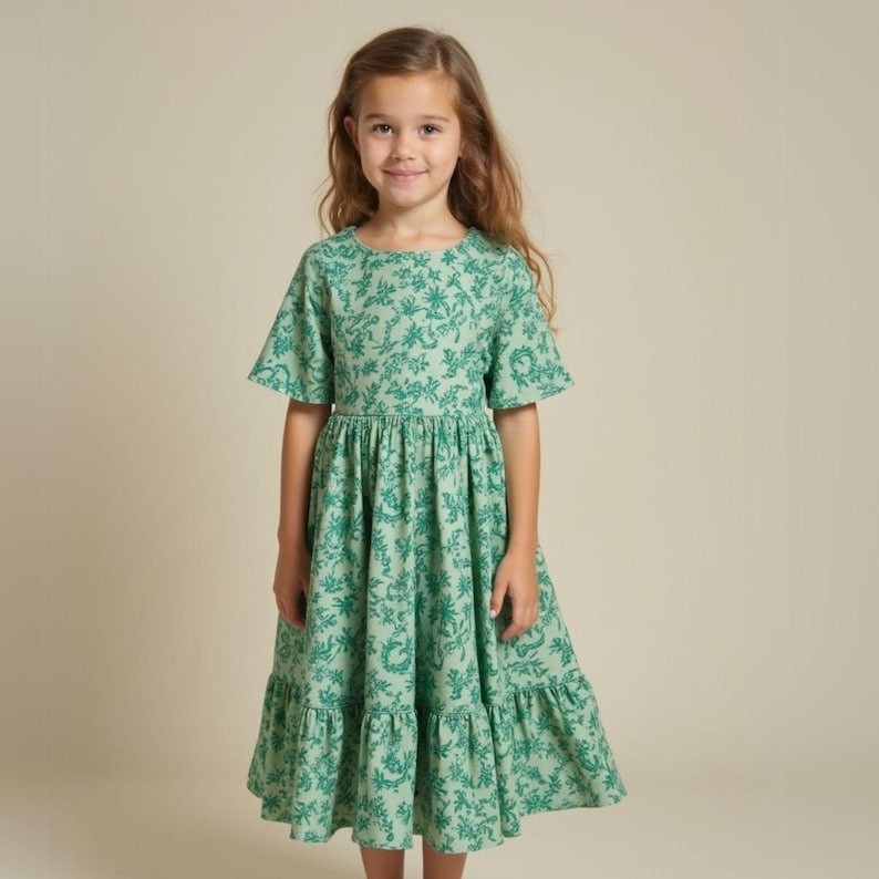 May include: A green floral print dress with a round neckline and short sleeves. The dress has a gathered waist and a tiered skirt.