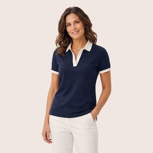 May include: A navy blue short-sleeved polo shirt featuring a white collar and white trim on the sleeve cuffs. The shirt has a deep V-neckline with a white placket detail and is paired with white trousers, creating a clean and simple look.