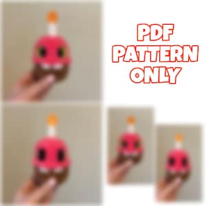 May include: A pink cupcake plushie with black eyes and a yellow candle. The image includes the text "PDF PATTERN ONLY". The cupcake has a brown base and is held in a hand. There are multiple images of the cupcake.