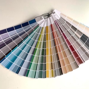 May include: A color fan deck with a variety of paint colors, including blues, greens, yellows, oranges, reds, and browns. The fan deck is open and fanned out, showing all of the colors.