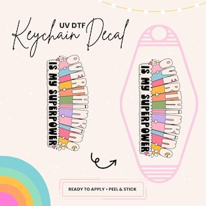 May include: A keychain decal with a pink background and a rainbow design. The text on the decal reads "Overthinking is my superpower".