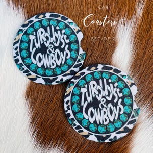 May include: Two white car coasters with a black and turquoise design. The coasters feature the text "Turquoise & Cowboys" in a bold, stylized font.