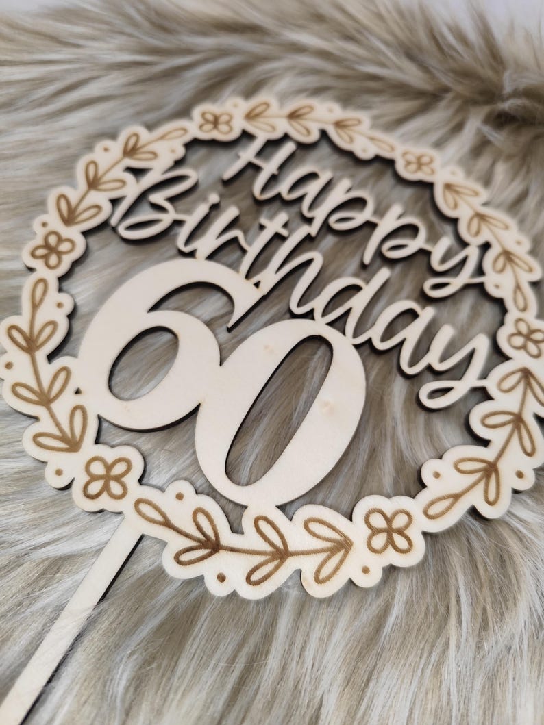 May include: Wooden cake topper with a floral wreath design and the text "Happy Birthday 60".