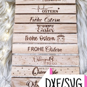 May include: A set of eight wooden signs with different Easter greetings in German and English. The signs are all made of natural wood and have a rustic look. The greetings include "Ein Gruß vom Osterhasen", "Frohe Ostern", "Happy Easter", and "Ostergruß to go".