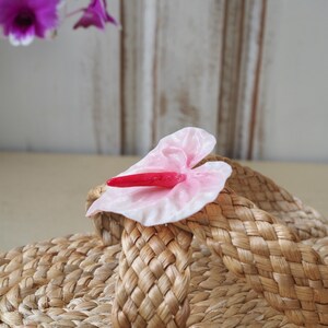 May include: A pair of woven straw sandals with a pink and red flower embellishment.