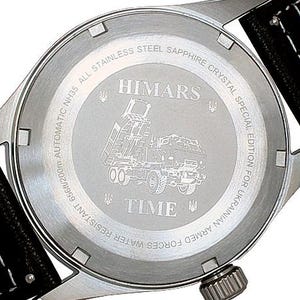 Puede incluir: La parte posterior de un reloj plateado con una correa de cuero negro. La esfera del reloj tiene las palabras "HIMARS" y "TIME" grabadas. El reloj es una edici&oacute;n especial para las Fuerzas Armadas de Ucrania.