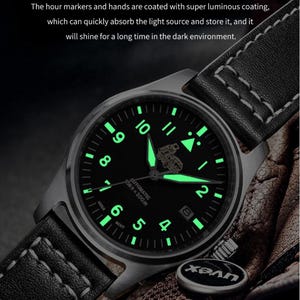 Puede incluir: Un reloj de pulsera negro con una correa de cuero negro y manecillas e &iacute;ndices luminosos verdes. La esfera del reloj tiene el texto "AUTOMATIC 556-200m" y un peque&ntilde;o tri&aacute;ngulo en la posici&oacute;n de las 12 en punto. El reloj se ilumina en la oscuridad.