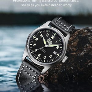 Puede incluir: Un reloj de pulsera negro y plateado con una correa de cuero negro. La esfera del reloj tiene marcas blancas y una ventana de fecha. El reloj es resistente al agua hasta 200 metros.