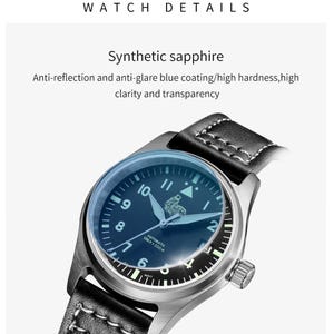 Puede incluir: Un reloj negro con caja plateada y correa de cuero negro. La esfera del reloj tiene marcas blancas y una esfera azul con el texto "AUTOMATIC 556 ft 200m". El reloj tiene un cristal de zafiro sint&eacute;tico con revestimiento antirreflectante y antideslumbrante azul.