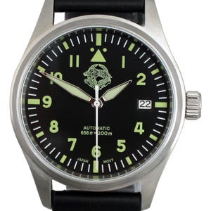 May include: A stainless steel wristwatch with a black face and a black leather strap. The watch face has luminous hands and markers, with the text "AUTOMATIC 656 ft = 200m" and the number "22". The watch includes a date display.