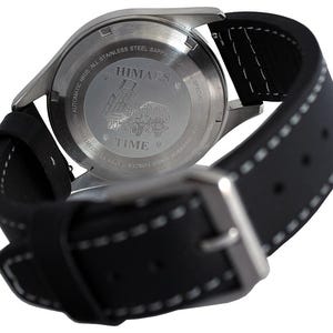 Puede incluir: Vista posterior de una correa de reloj de cuero negro con costuras blancas. La esfera del reloj es de acero inoxidable y presenta el texto "HIMARS" y "TIME" en un dise&ntilde;o circular.