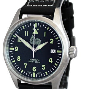 Puede incluir: Un reloj de pulsera negro y plateado con una correa de cuero negro. La esfera del reloj tiene un fondo negro con marcas blancas y una peque&ntilde;a imagen de un cami&oacute;n. El reloj est&aacute; etiquetado como "Automatic 656 ft = 200m" y "Japan Movt". La correa del reloj tiene costuras blancas. El reloj est&aacute; etiquetado como "Edici&oacute;n especial para las fuerzas armadas ucranianas".