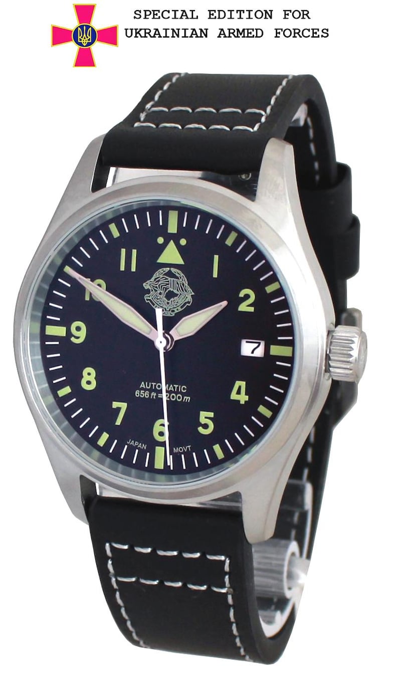 May include: A silver wristwatch with a black dial, luminous hands, and white numerals. The watch features a black leather strap with white stitching. The watch face displays "AUTOMATIC 656 ft = 200m" and "JAPAN MOVT". The text "SPECIAL EDITION FOR UKRAINIAN ARMED FORCES" is above the watch.