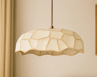 May include: A pendant light fixture featuring a dome-shaped shade with a textured, off-white, segmented surface and gold-toned edges. The shade is suspended from a thin, straight rod connected to a matching gold-toned circular ceiling canopy.