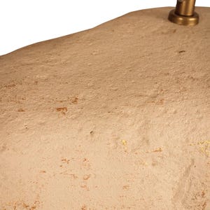 K&ouml;nnte beinhalten: Eine beige, organisch geformte Pendelleuchte. Die Leuchte hat eine strukturierte Oberfl&auml;che mit dezenten Goldakzenten. Ein messingfarbener Stiel und eine Halterung verbinden sich mit der Decke.