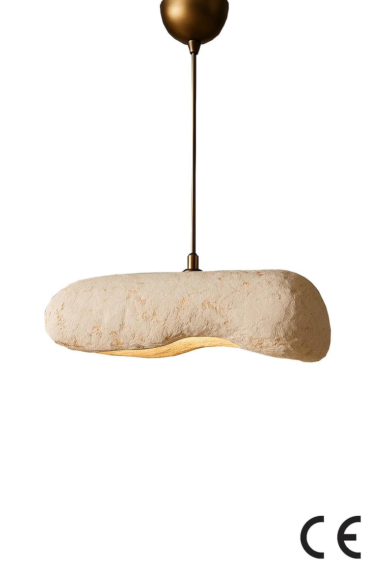 K&ouml;nnte beinhalten: H&auml;ngeleuchte mit einem strukturierten, l&auml;nglichen, cremefarbenen Schirm. Der Schirm h&auml;ngt an einem bronzefarbenen Stiel und einer Deckenhalterung. Die Leuchte hat ein modernes, minimalistisches Design. Ca. 40 cm lang.