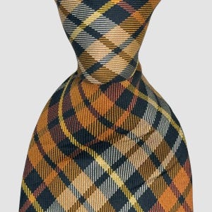 Puede incluir: Una corbata con un patr&oacute;n de cuadros tejido en tonos azul marino oscuro, amarillo mostaza, naranja quemado y blanco. La tela tiene una textura diagonal visible y el dise&ntilde;o consiste en l&iacute;neas que se cruzan formando una cuadr&iacute;cula cl&aacute;sica.