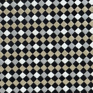 May include: Close-up of a fabric with a repeating diamond pattern. The diamonds are in black, white, silver, and tan. The fabric has a textured appearance, suggesting a woven or embroidered design. The pattern is symmetrical and creates a visually interesting surface.
