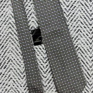 May include: A black, white, and tan checkered tie with a matching tie. The tie has a small, repeating square pattern. The tag reads "JIM THOMPSON".