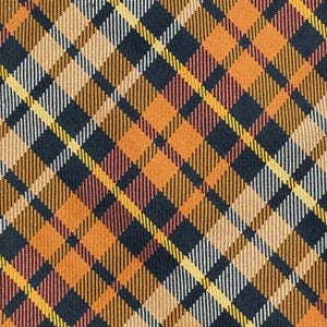 Puede incluir: Una tela con un patr&oacute;n de cuadros diagonal en tonos negro, naranja, amarillo y blanco. El dise&ntilde;o consiste en l&iacute;neas y bloques de color que se cruzan para crear una cuadr&iacute;cula geom&eacute;trica repetitiva en toda la superficie del material.