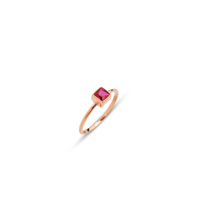 Op de afbeelding: Een eenvoudige gouden ring met een vierkante roze edelsteen.