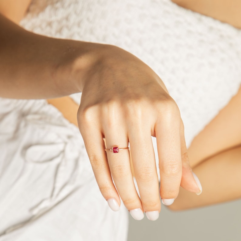 Op de afbeelding: Een gouden ring met een vierkante rode edelsteen.