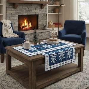 Könnte beinhalten: Ein Couchtisch aus dunklem Holz mit einem blau-weiß gemusterten Tischläufer. Der Läufer hat ein geometrisches Schneeflockenmuster. Eine Tasse heiße Schokolade, eine Schneekugel und zwei blaue Sessel schaffen eine gemütliche Winteratmosphäre.