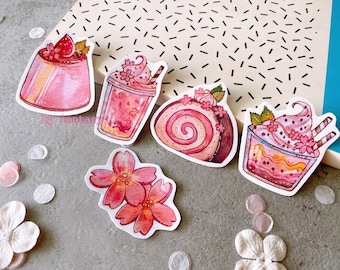 May include: Five pink and white themed stickers featuring a variety of desserts. The stickers include a pink pudding with a strawberry on top, a pink and white swirl cake, a pink and white milkshake, a pink and white parfait, and a pink and white flower.