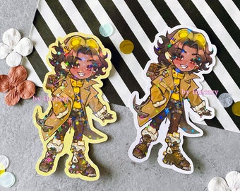 May include: Two holographic stickers featuring a cartoon character with brown hair, wearing a yellow shirt, brown jacket, and goggles. The character is holding a tool in one hand and has a backpack on their back. The stickers are on a striped background with the text "by imntary" on each sticker.