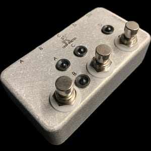 May include: A silver metal foot pedal with four footswitches labeled A, B, C, and D. The pedal has the text "LOOP-MASTER" printed on it.