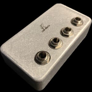 May include: A silver metal box with four jacks on the top. The box is labeled "LOOP-MASTER".
