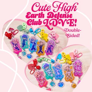 Könnte beinhalten: Eine Sammlung farbenfroher, doppelseitiger Schlüsselanhänger mit Anime-Charakteren. Die Schlüsselanhänger haben verschiedene Farben und Designs, mit dem Text "Cute High Earth Defense Club LOVE!"